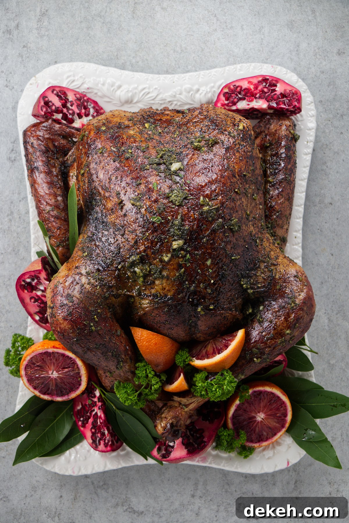 Smoked turkey on a platter served with citrus and herbs for garnish.