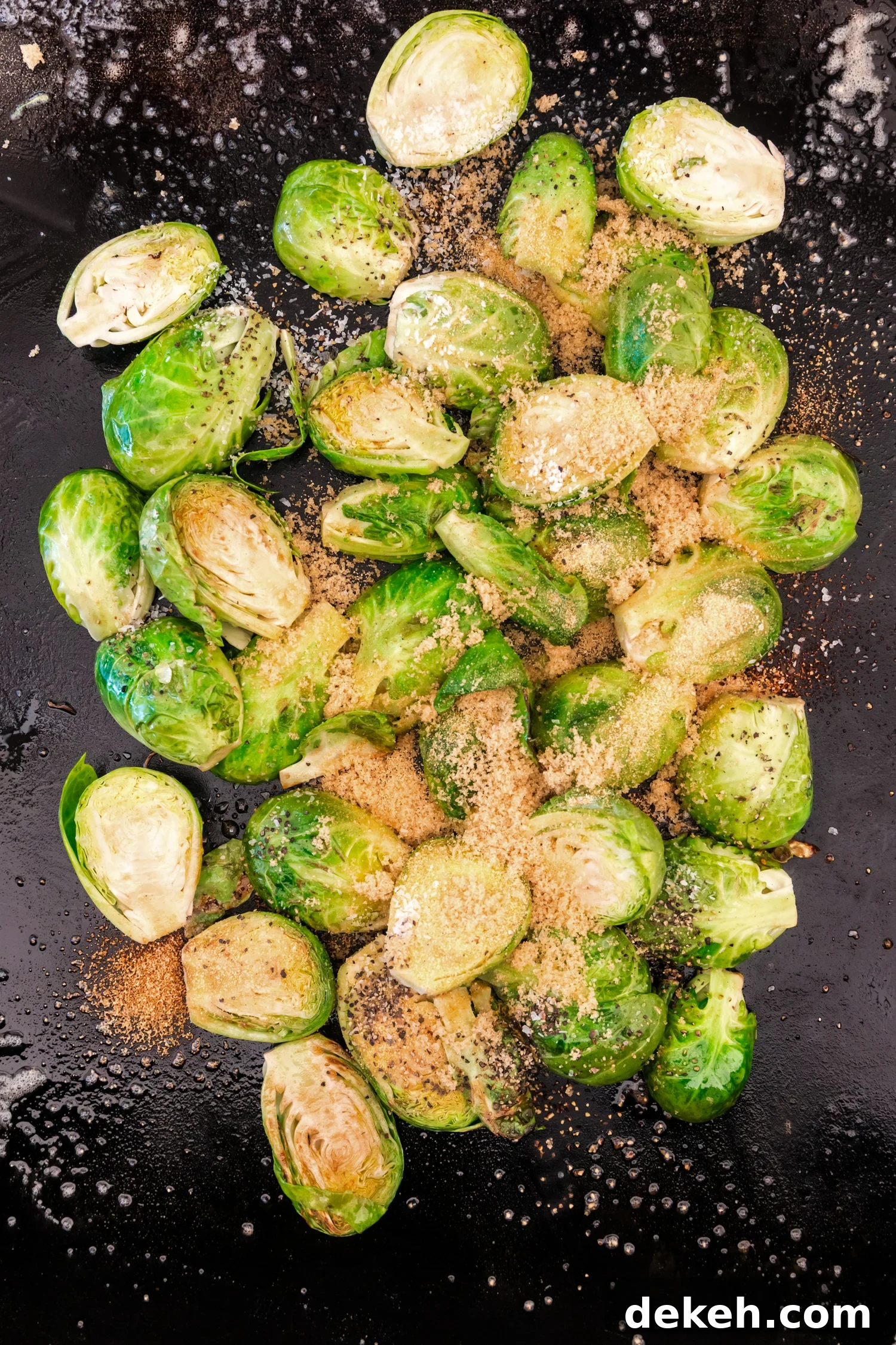 Brussels sprouts on a griddle sprinkled with brown sugar, salt, and black pepper for seasoning.