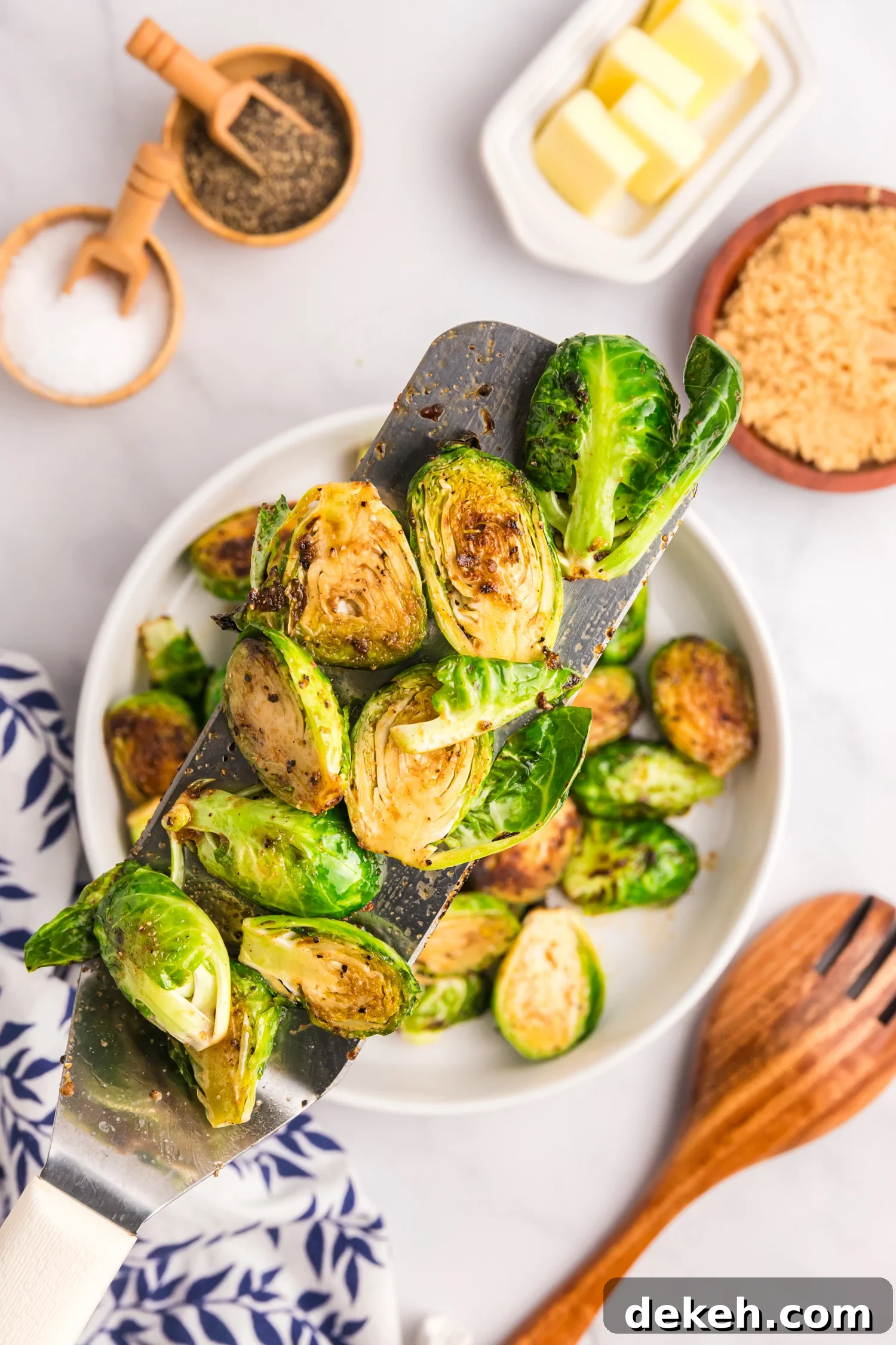 A close-up of cooked Brussels sprouts on a metal spatula, showing a crispy and caramelized surface.