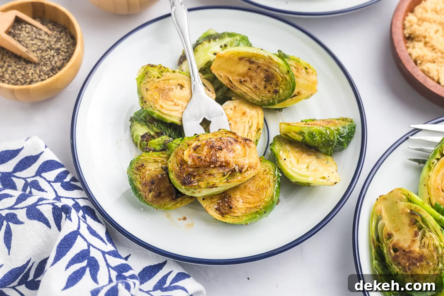 Plated roasted Brussels sprouts served on a white dish with a fork, ready to eat.