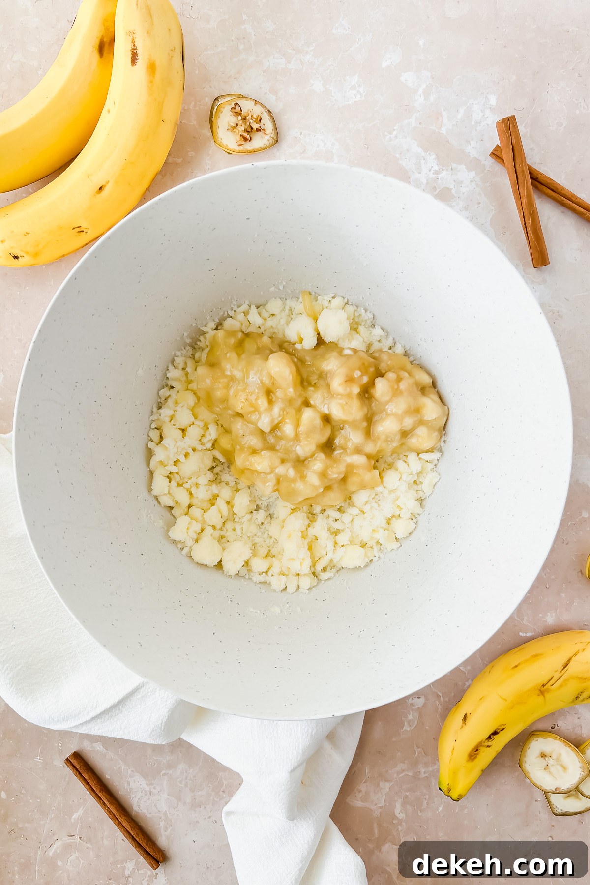 butter, sugar, and mashed banana in white mixing bowl.