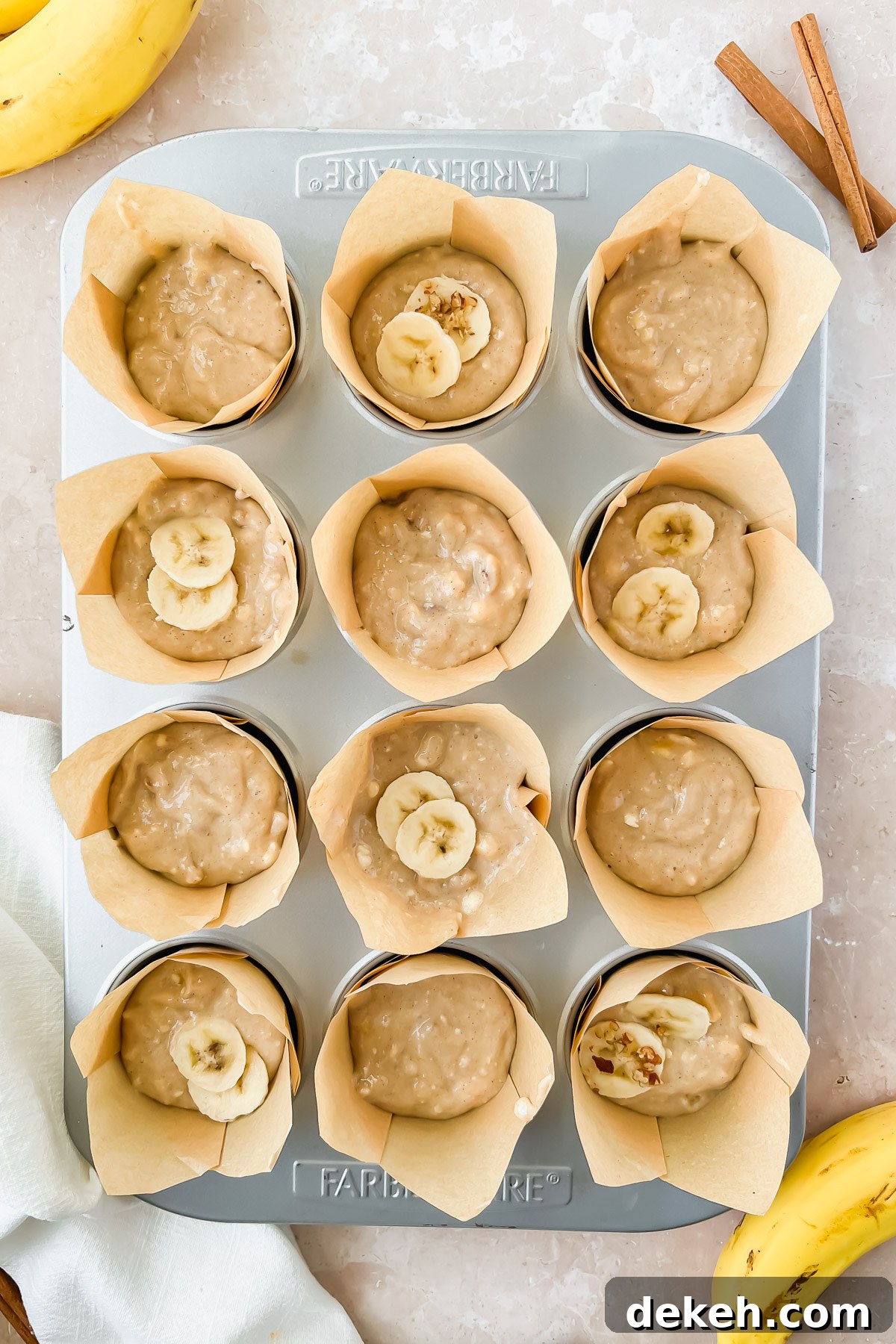 muffin tin lined with parchment cupcake liners filled with greek yogurt banana muffin batter.
