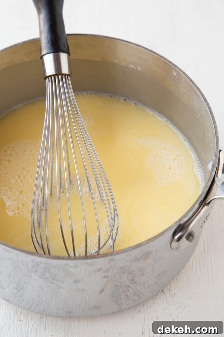yellow lemon and egg liquid mixture in a saucepan with a whisk.