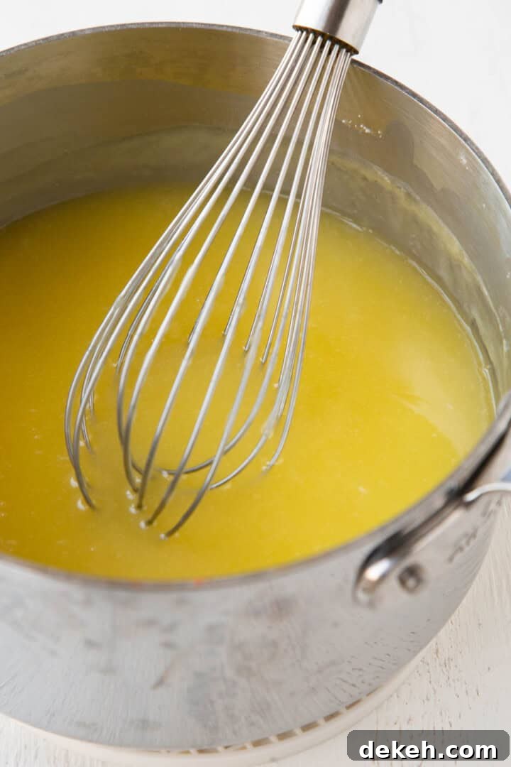 yellow firm liquid mixture in a saucepan with a whisk.