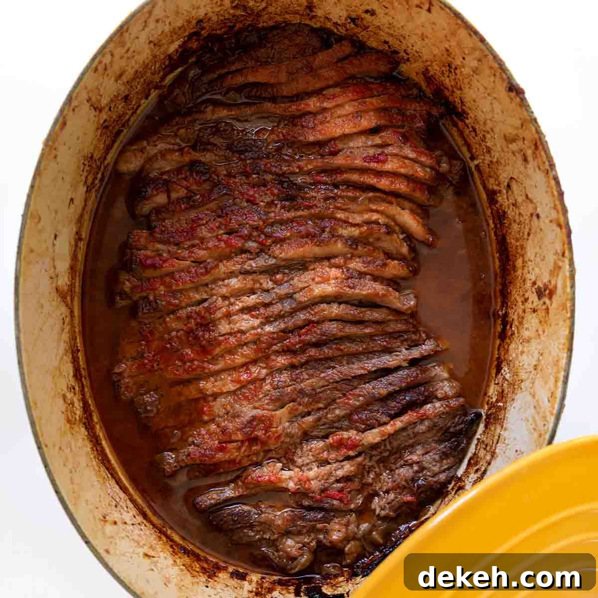 A yellow Le Creuset pot with Nach Waxman's sliced beef brisket inside.