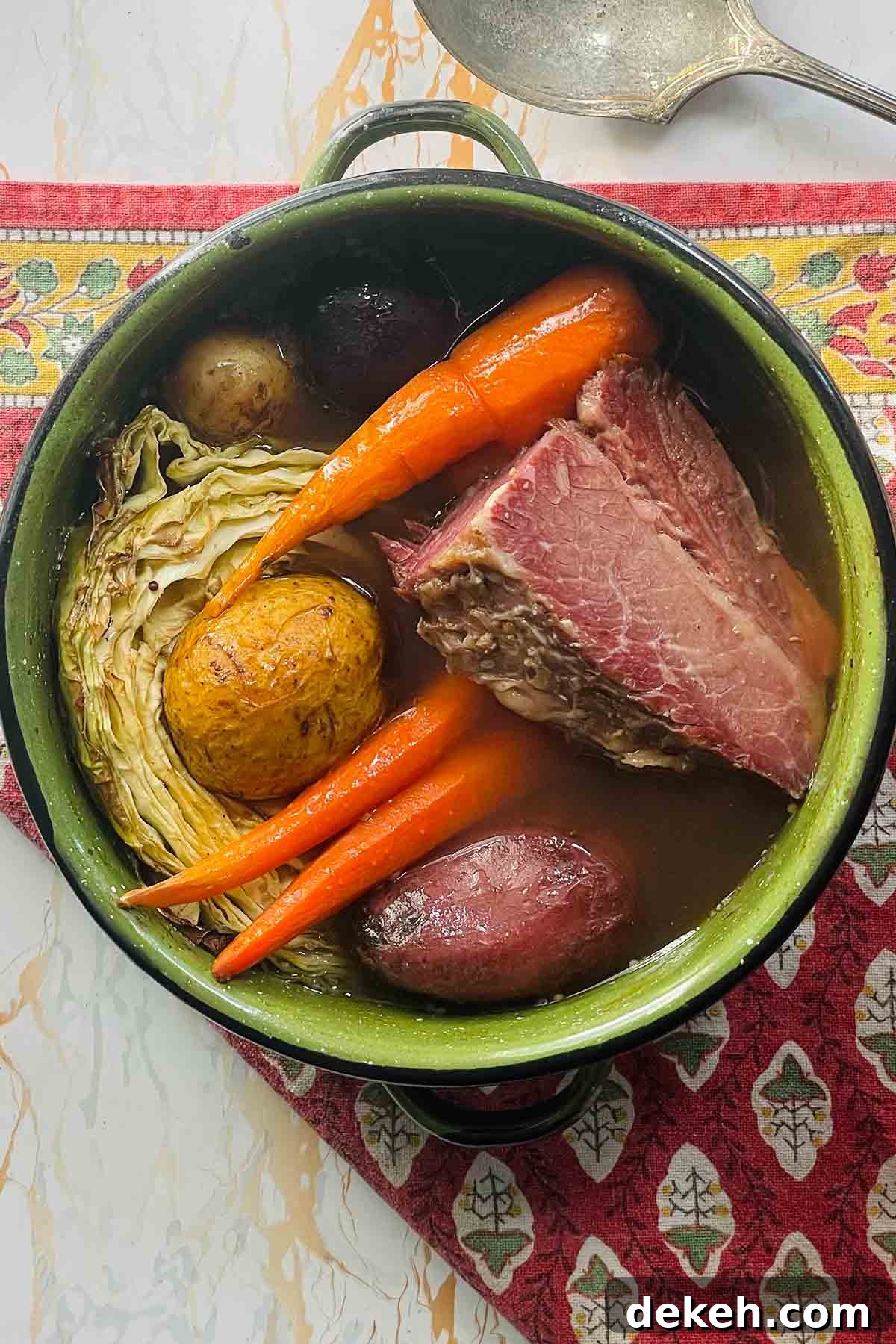 A pot filled with a chunk of corned beef, three carrots, cabbage, and potatoes.
