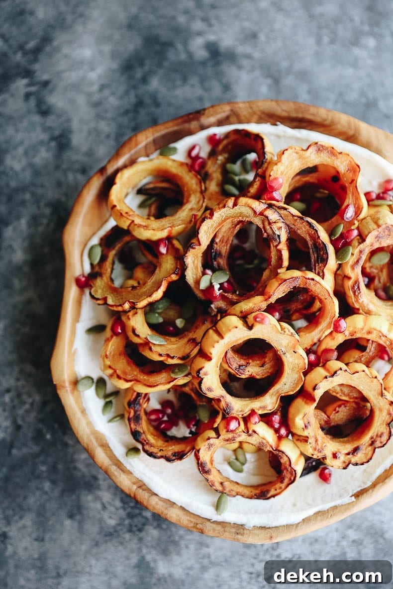 Roasted squash slices drizzled with tahini yogurt and garnished with pomegranate seeds and pepitas