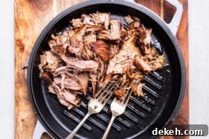 Pork being shredded with two forks.