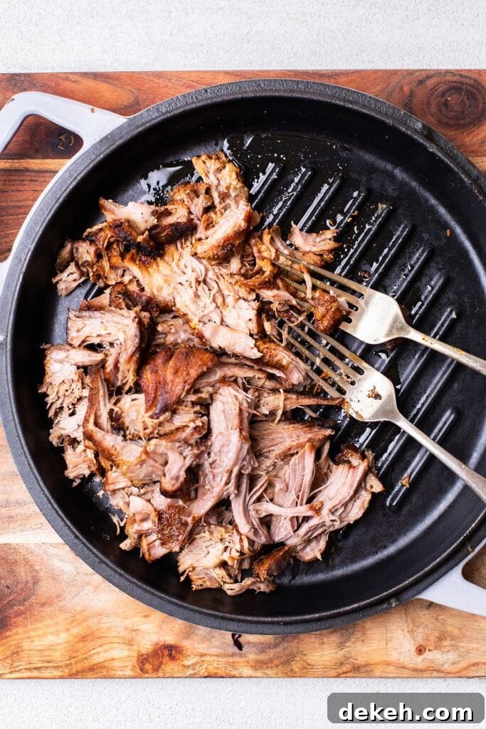 Pork being shredded with two forks.