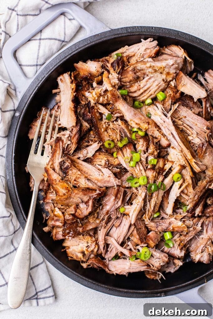 A dish showing pulled pork garnished with green onions with no bbq sauce.
