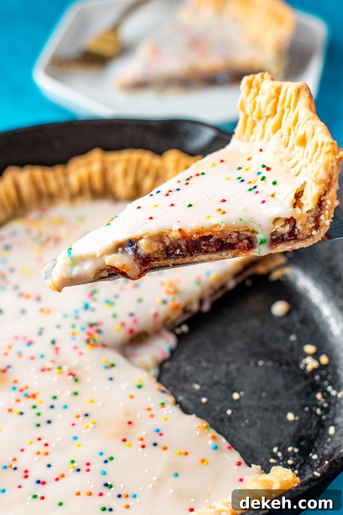Lifting a slice of a skillet inspired strawberry Pop Tart pie out of a cast iron skillet.