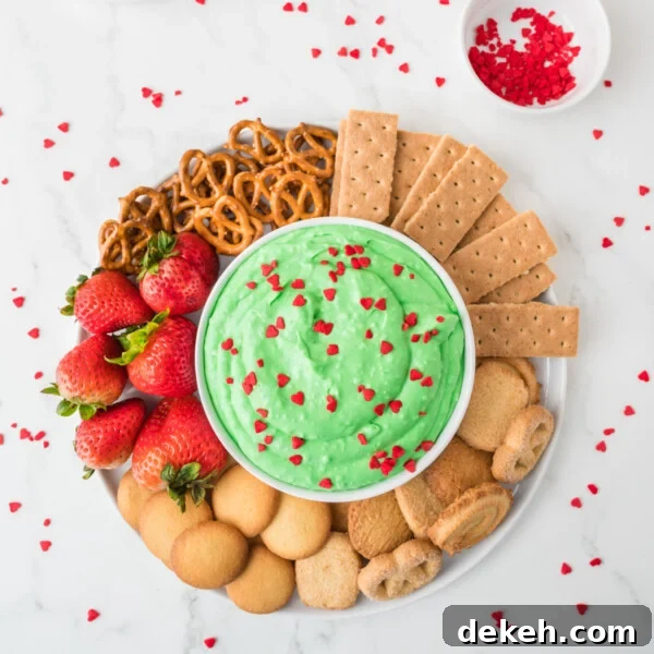 An overhead image of grinch dip in the center with an assortment of crackers, biscuits, pretzels, and strawberries on the side.