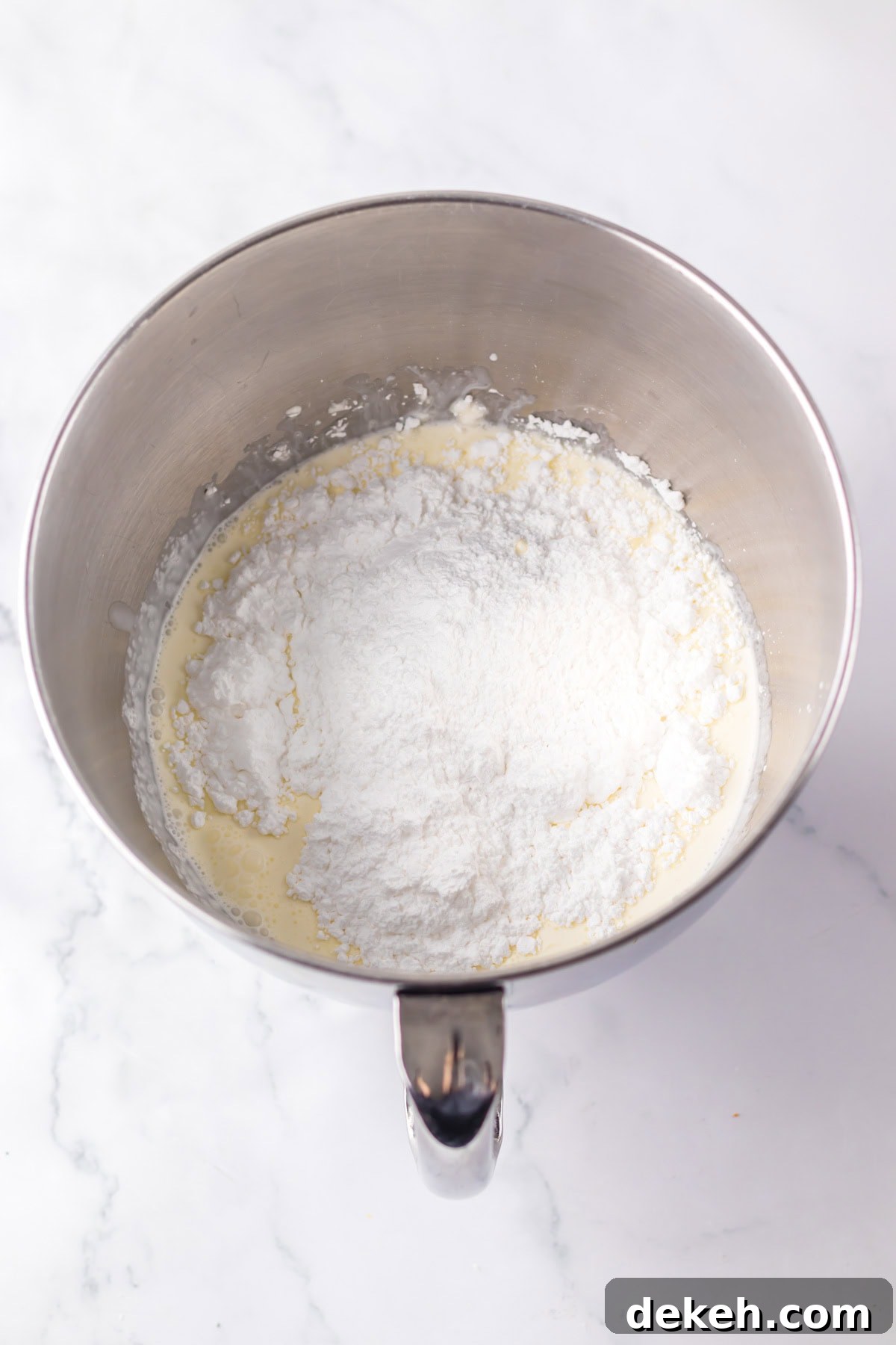 An overhead image of combining powdered sugar and whipped cream.