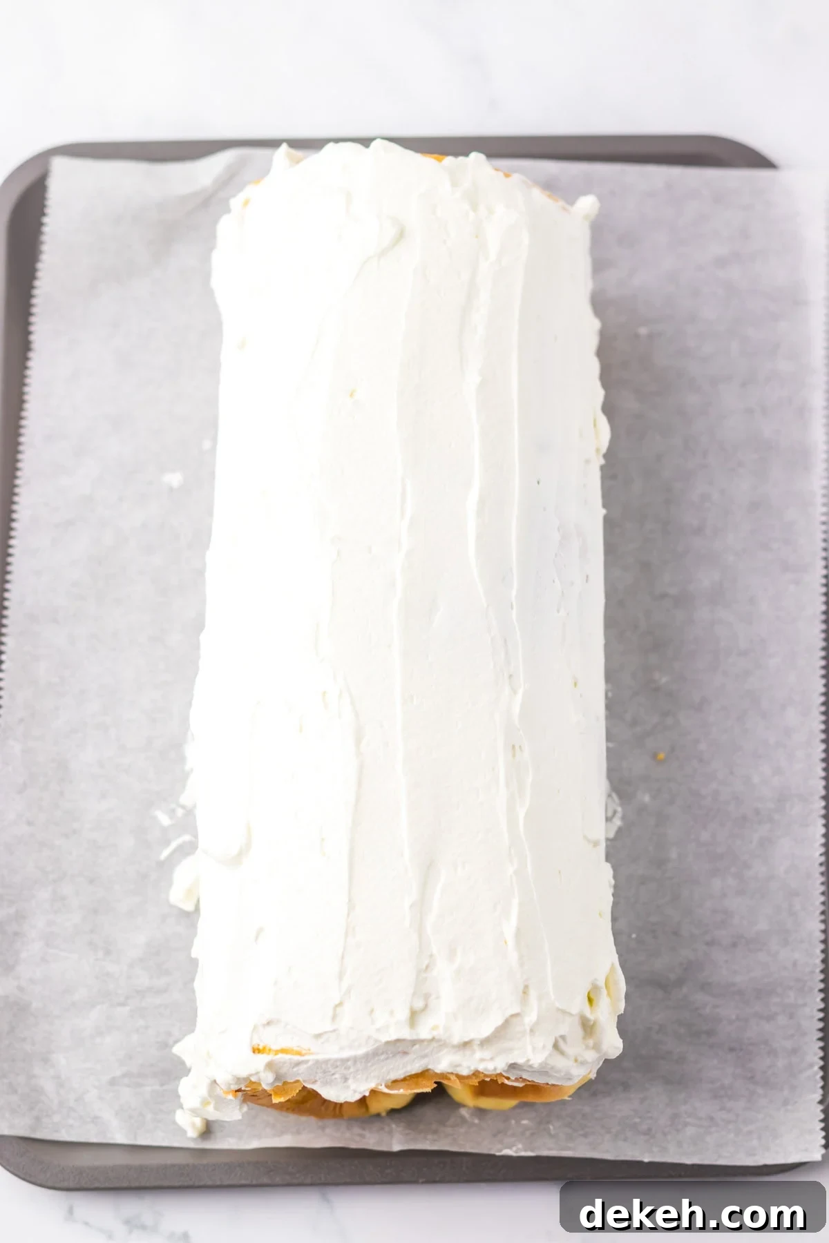 An overhead image of spreading the frosting to the cake roll.