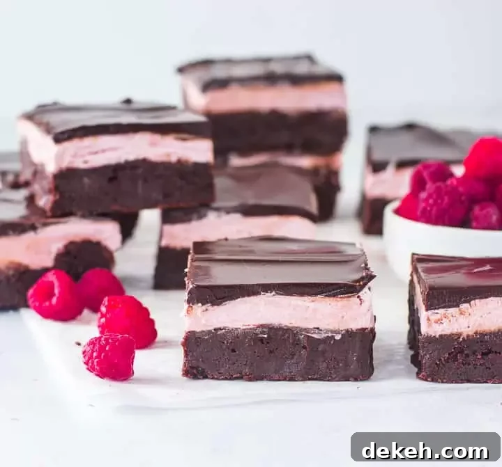 raspberry brownies on a piece of parchment paper with more brownies in the background
