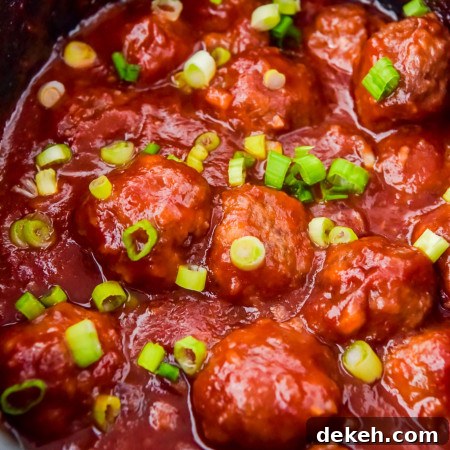Cranberry meatballs in sauce in the slow cooker garnished with sliced green onions