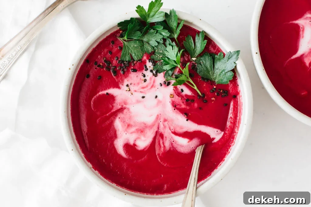 Beet soup in a bowl garnished with coconut cream and parsley.