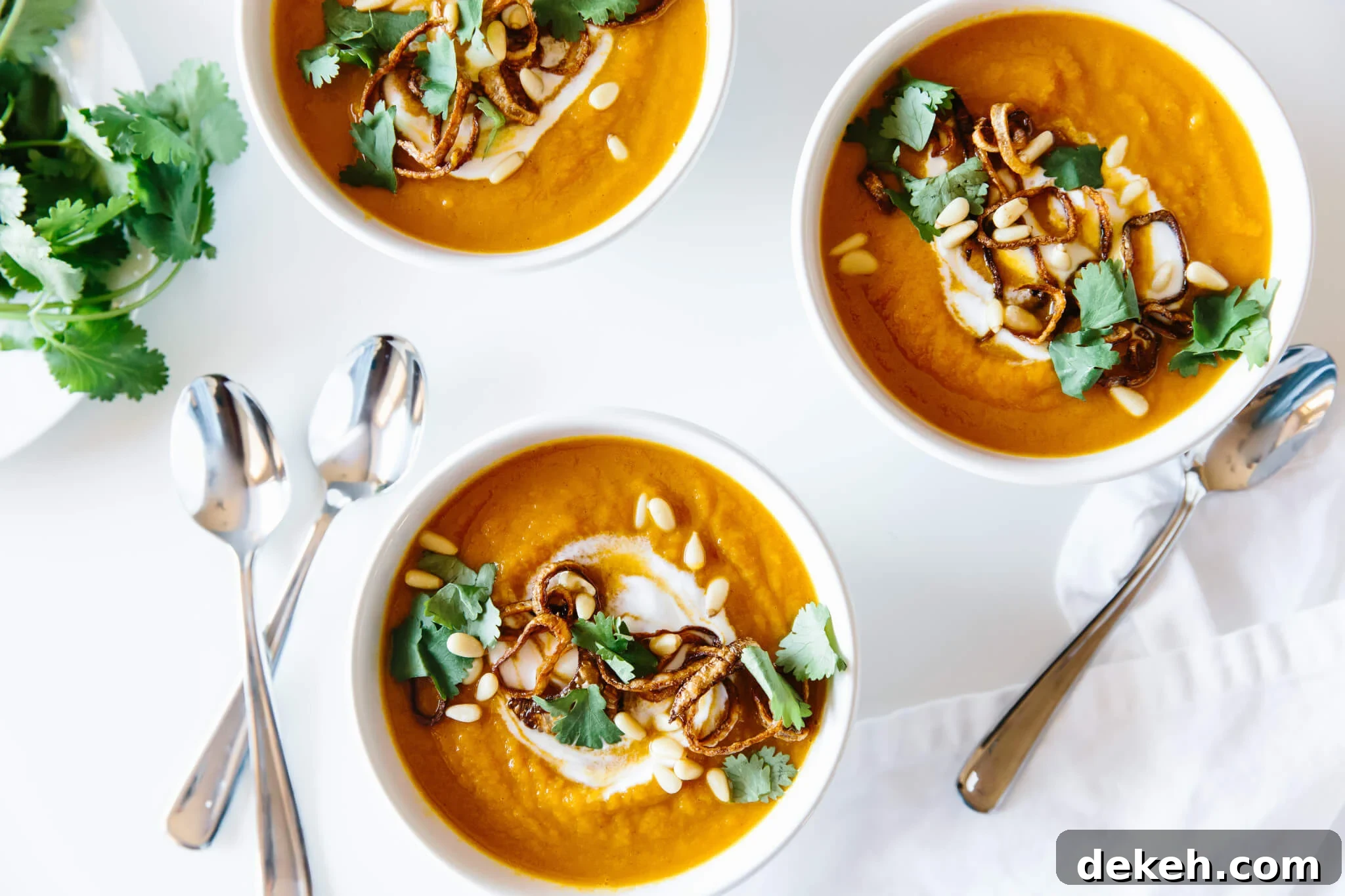 Several bowls of carrot ginger soup on a table.