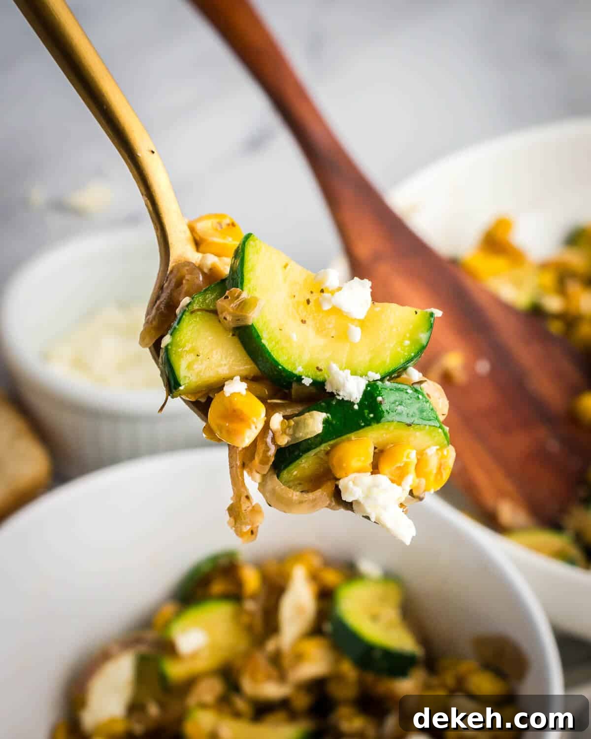 a bite of sauteed zucchini, corn, and shallots on a fork. 