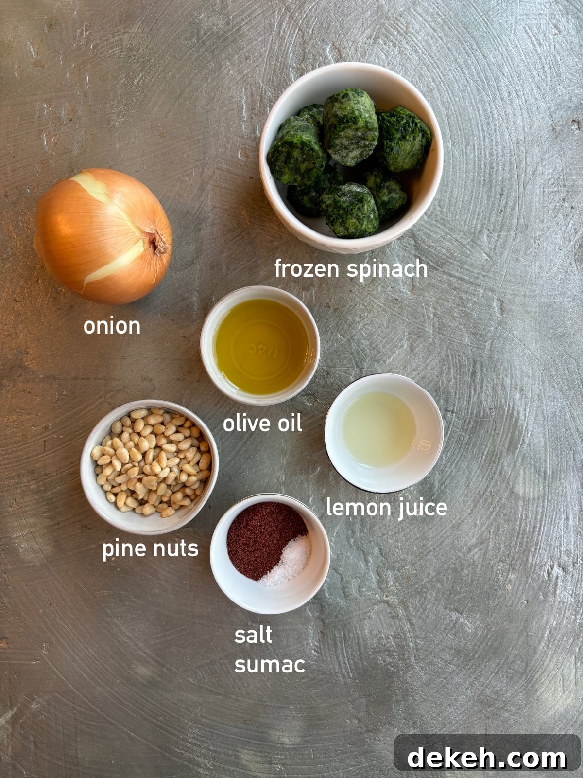 overhead shot of the ingredients needed to make the filling for Fatayer Spinach Pies. Each ingredient is in a small bowl and labeled with white text.