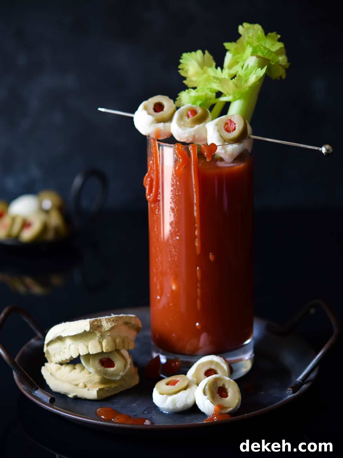 Bloody Mary with celery and mozzarella garnish on a black background.