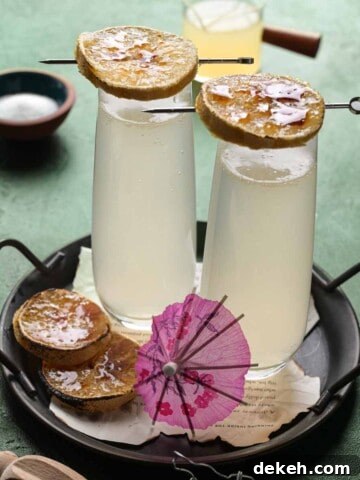Two lemonade mimosas on a green background with lemons on top.