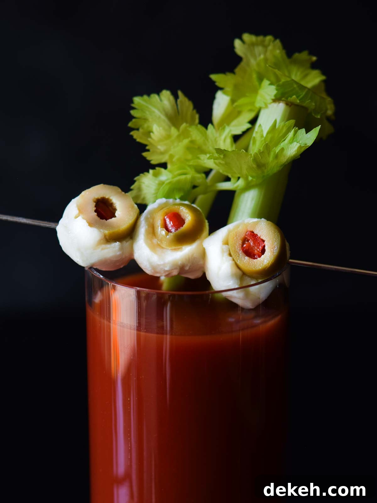 Close up of mozzarella and olives on a cocktail pick resembling eyeballs.