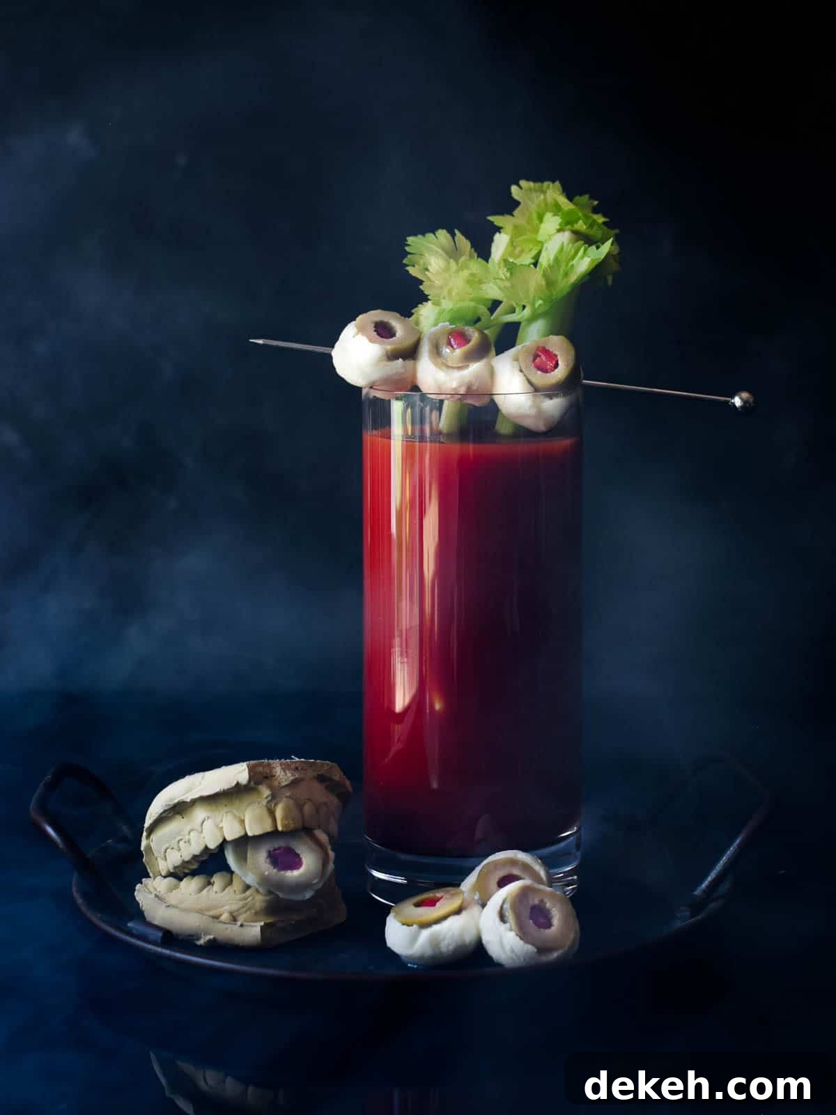 Bloody Mary with celery and mozzarella garnish on a black background.