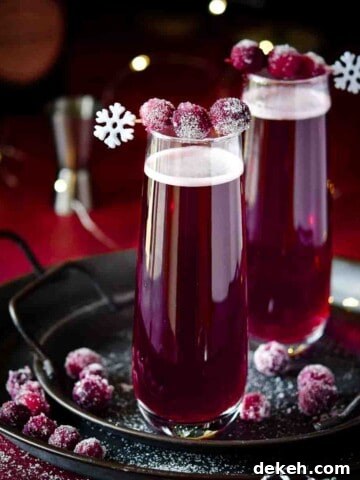 Cranberry mimosas with sugared cranberries on a black tray.