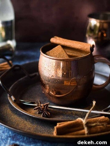 Chai Moscow mule in a copper mug with a cinnamon stick on fire.