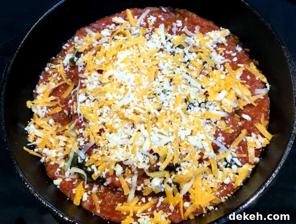 roasted poblano peppers stuffed with cheese in a pan with salsa.