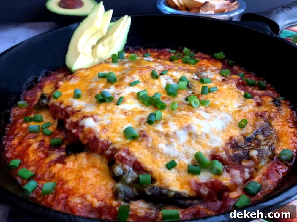 baked chile rellenos in a cast iron pan topped with green onion and avocado