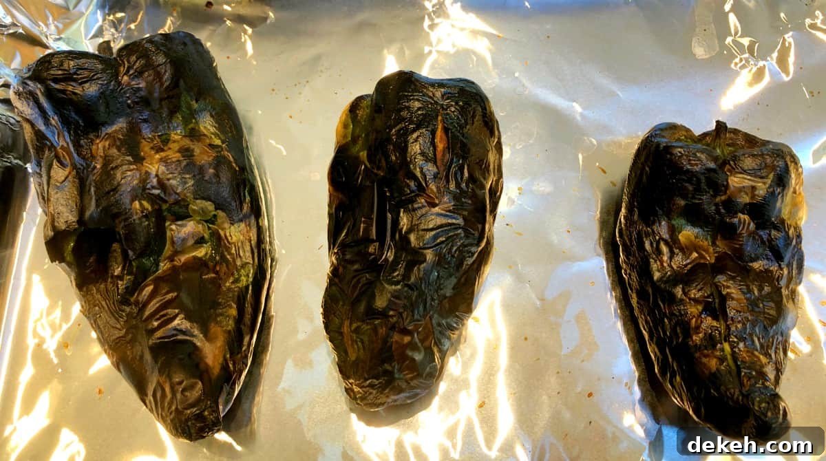 roasted poblano peppers on a baking sheet with tin foil.