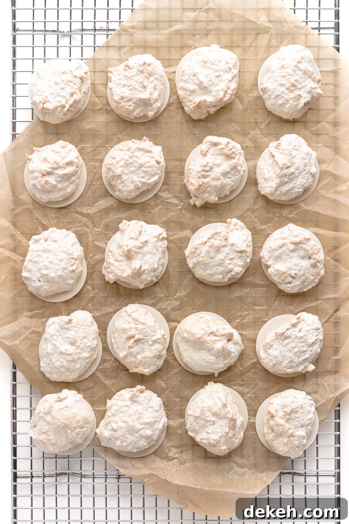Kokosmakronen (German Coconut Macaroons) on a piece of brown parchment paper set on a wire cooling rack.