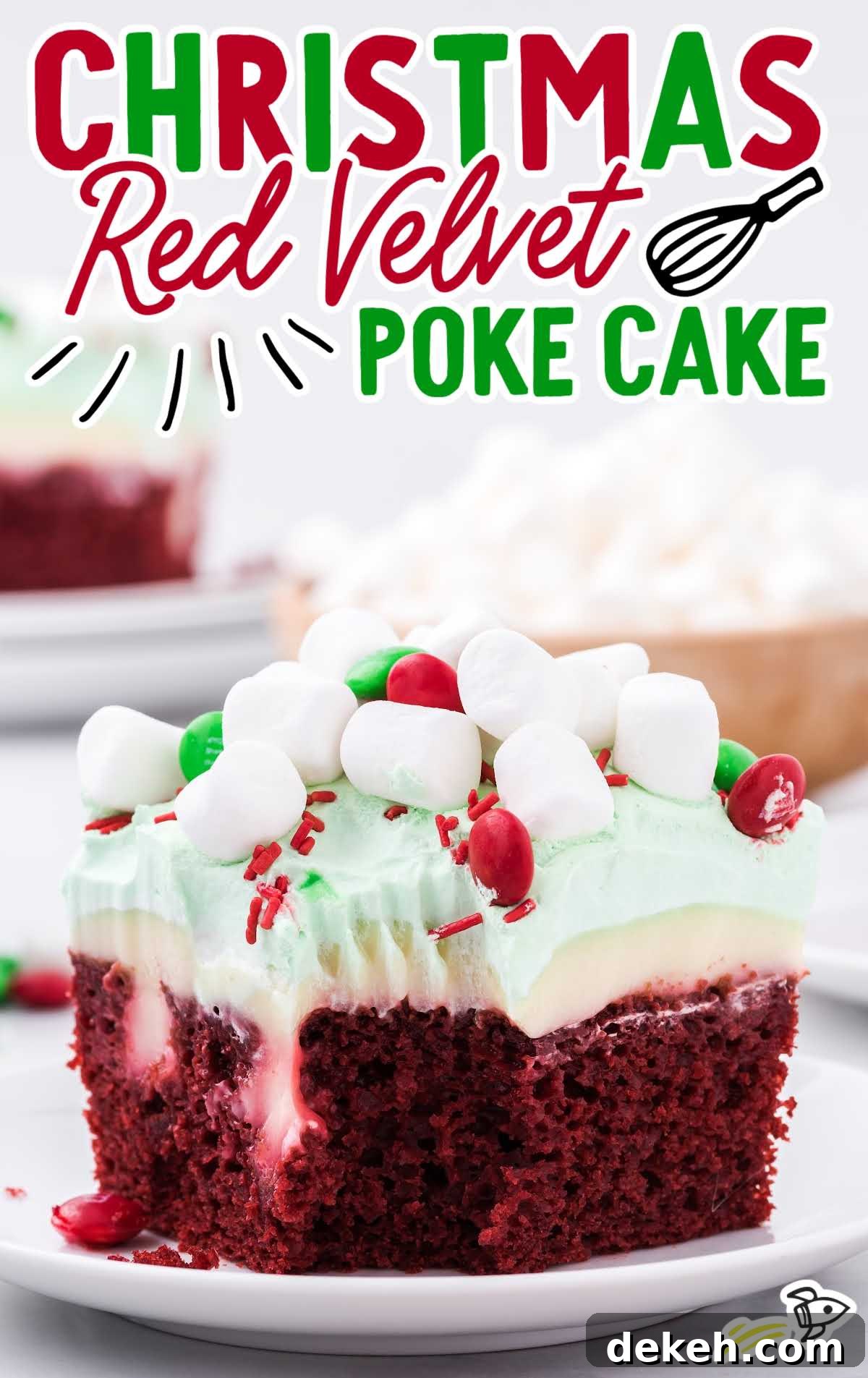 Slice of Christmas red velvet poke cake topped with green whipped cream, mini marshmallows, red and green M&M's, and festive sprinkles.