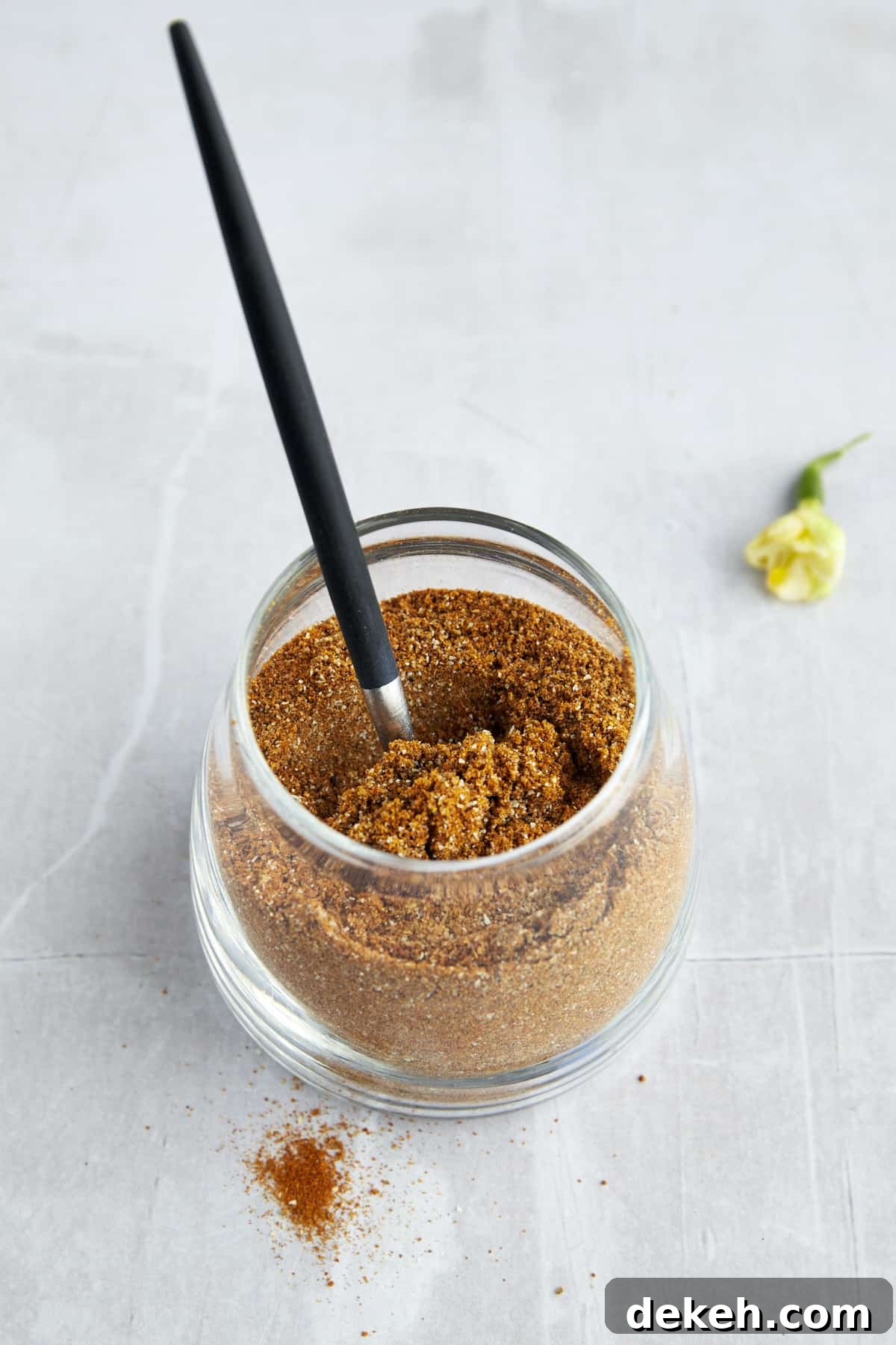 A jar of homemade shawarma seasoning with a spoon sticking out. 
