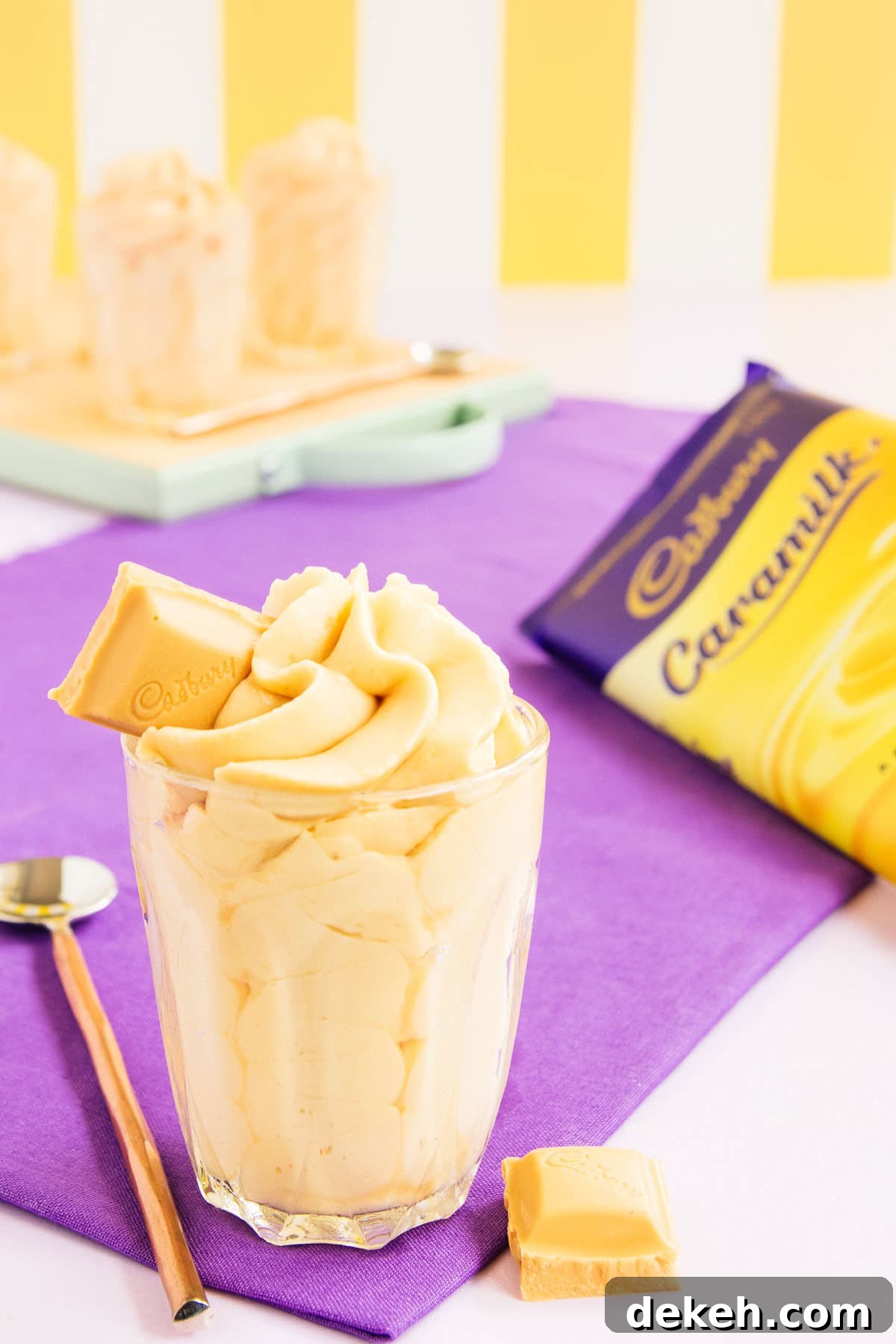 Mousse piped in a swirl into a small glass, with a block of Caramilk chocolate in the background. Text overlay reads: Easy Caramilk Mousse.