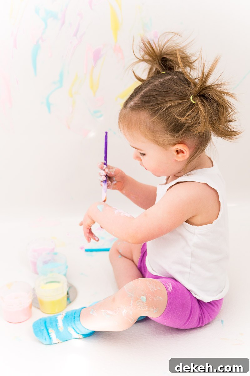 Toddler girl painting with bath paint.