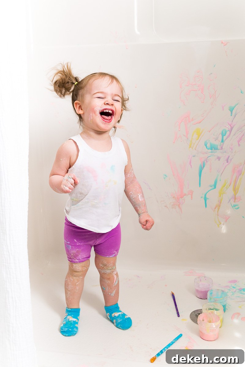 Toddler girl painting with bath paints.