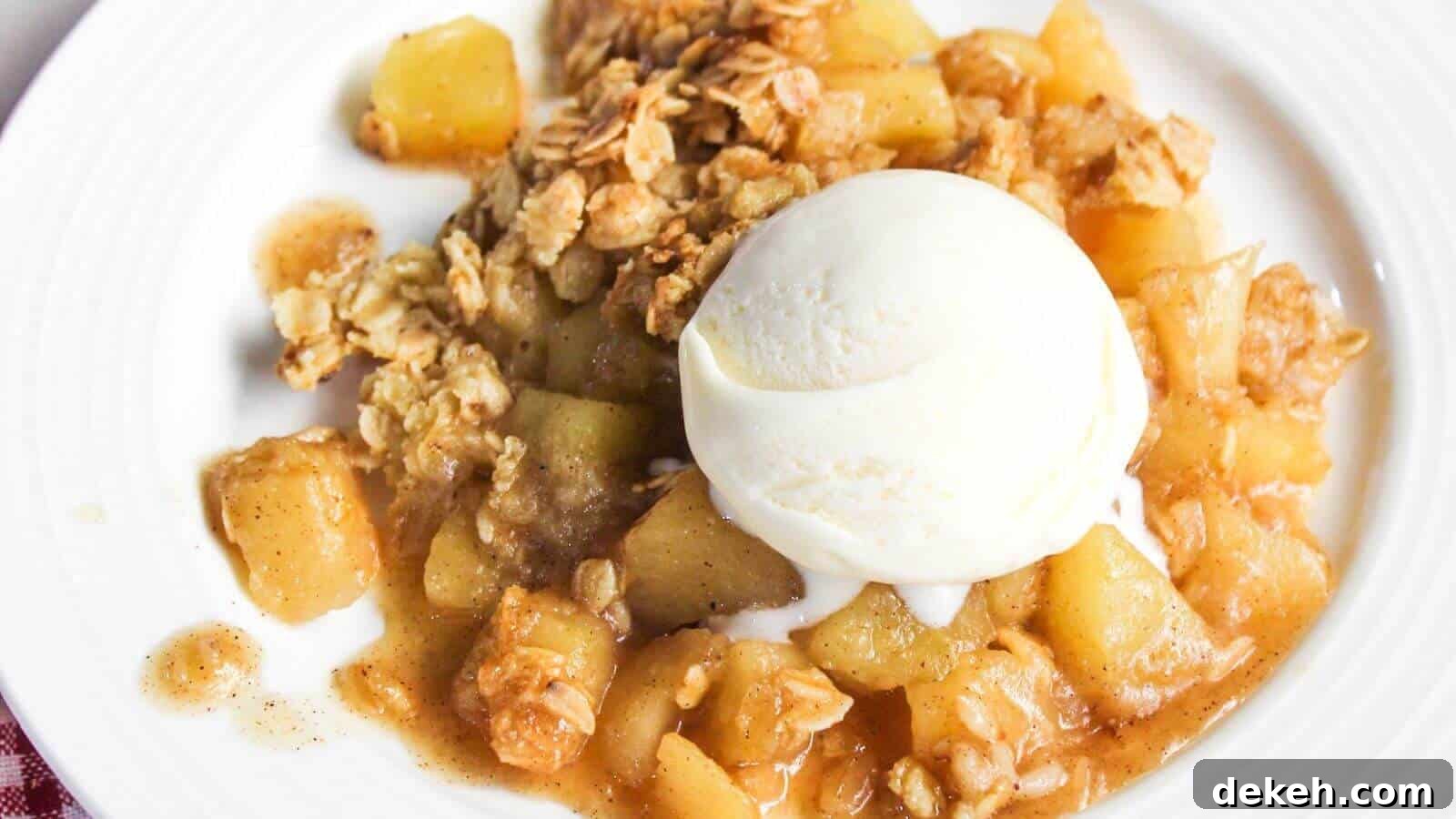 A plate of apple crisp with chunks of apple, topped with a scoop of vanilla ice cream and an oat crumble topping.