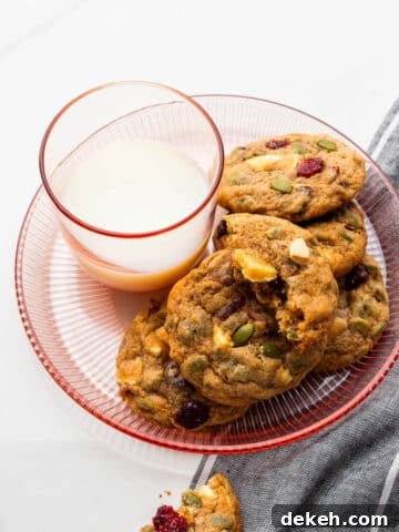 A glass of milk served with apple butter, cranberry, white chocolate chip cookies.