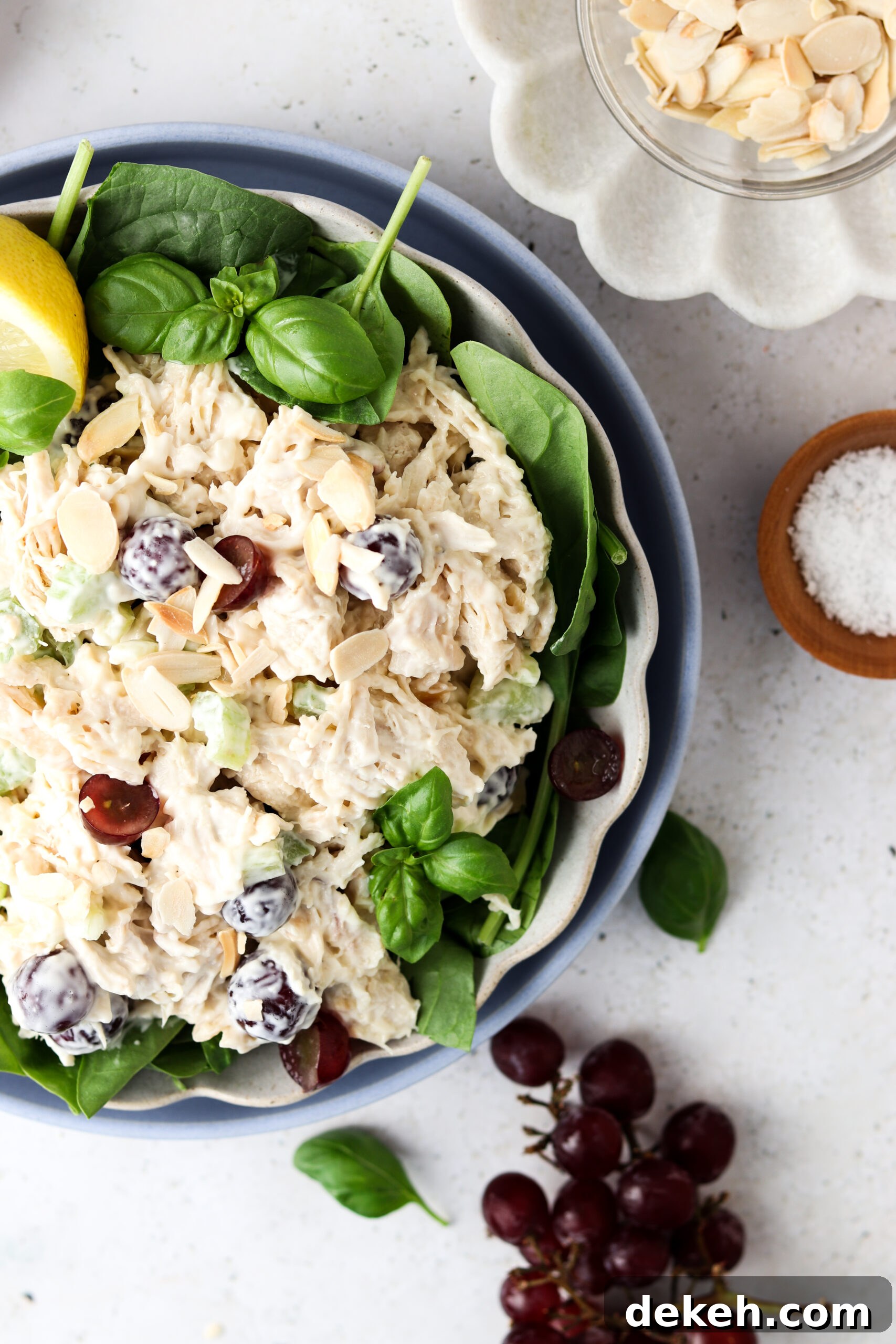 Whole30 chicken salad in a bowl over greens with grapes and almond slices.