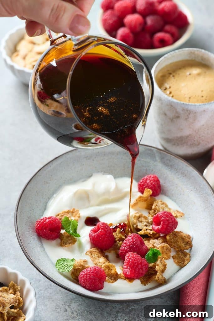 Date honey being poured over yogurt, granola and fruit.
