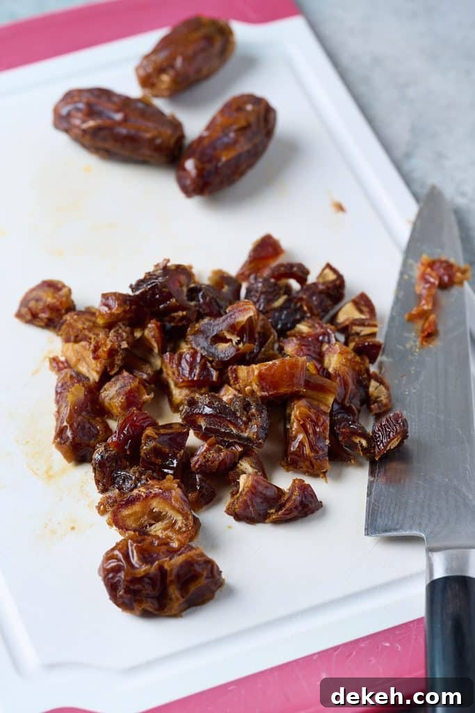 Chopped up dates on a cutting board. with the knife on the side 