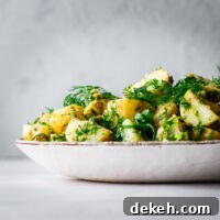 A herbed potato salad without mayonnaise piled high on a serving plate.