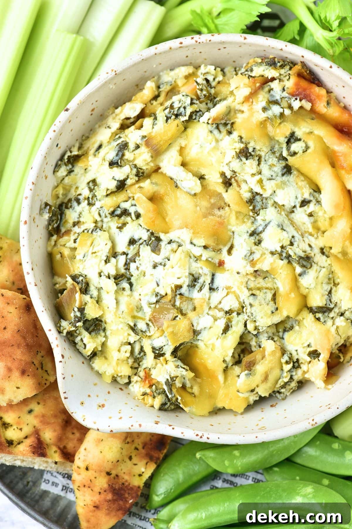 Top down view of bowl of creamy spinach artichoke dip.