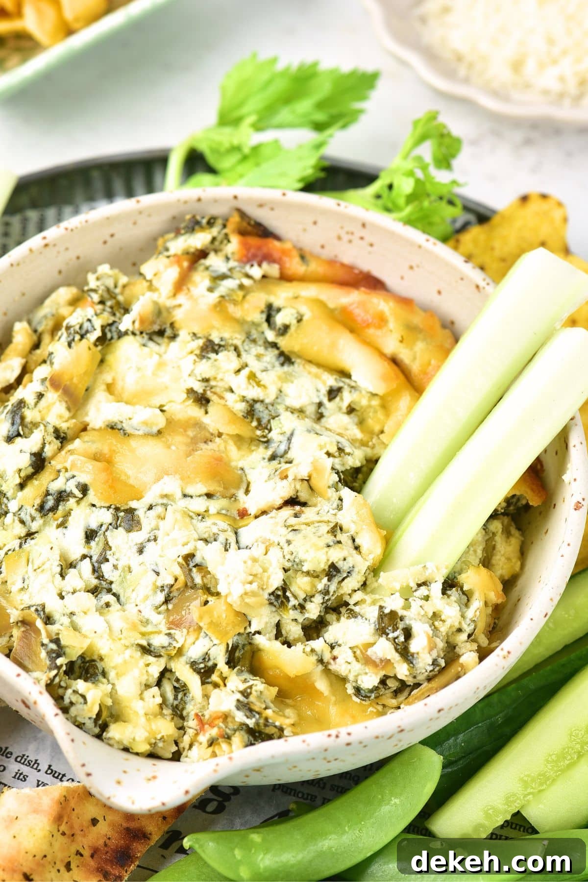 Celery sticks in a bowl of artichoke dip