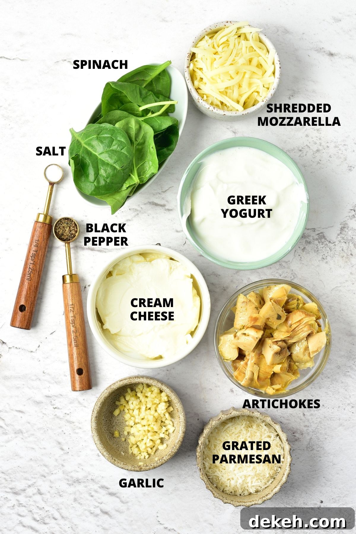 Ingredients for spinach artichoke dip recipe laid out on marble board