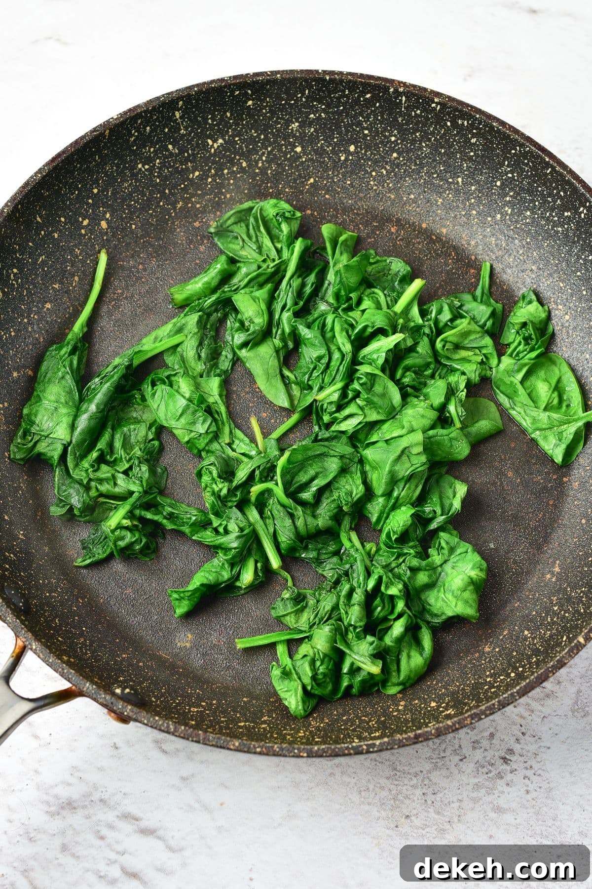 Wilted spinach leaves in skillet