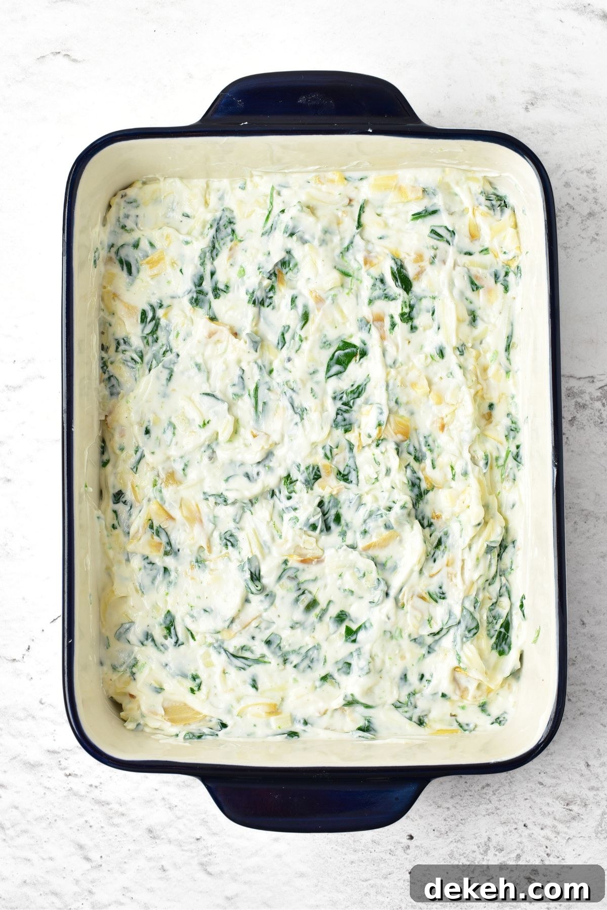 A baking dish with spinach and artichoke mixture
